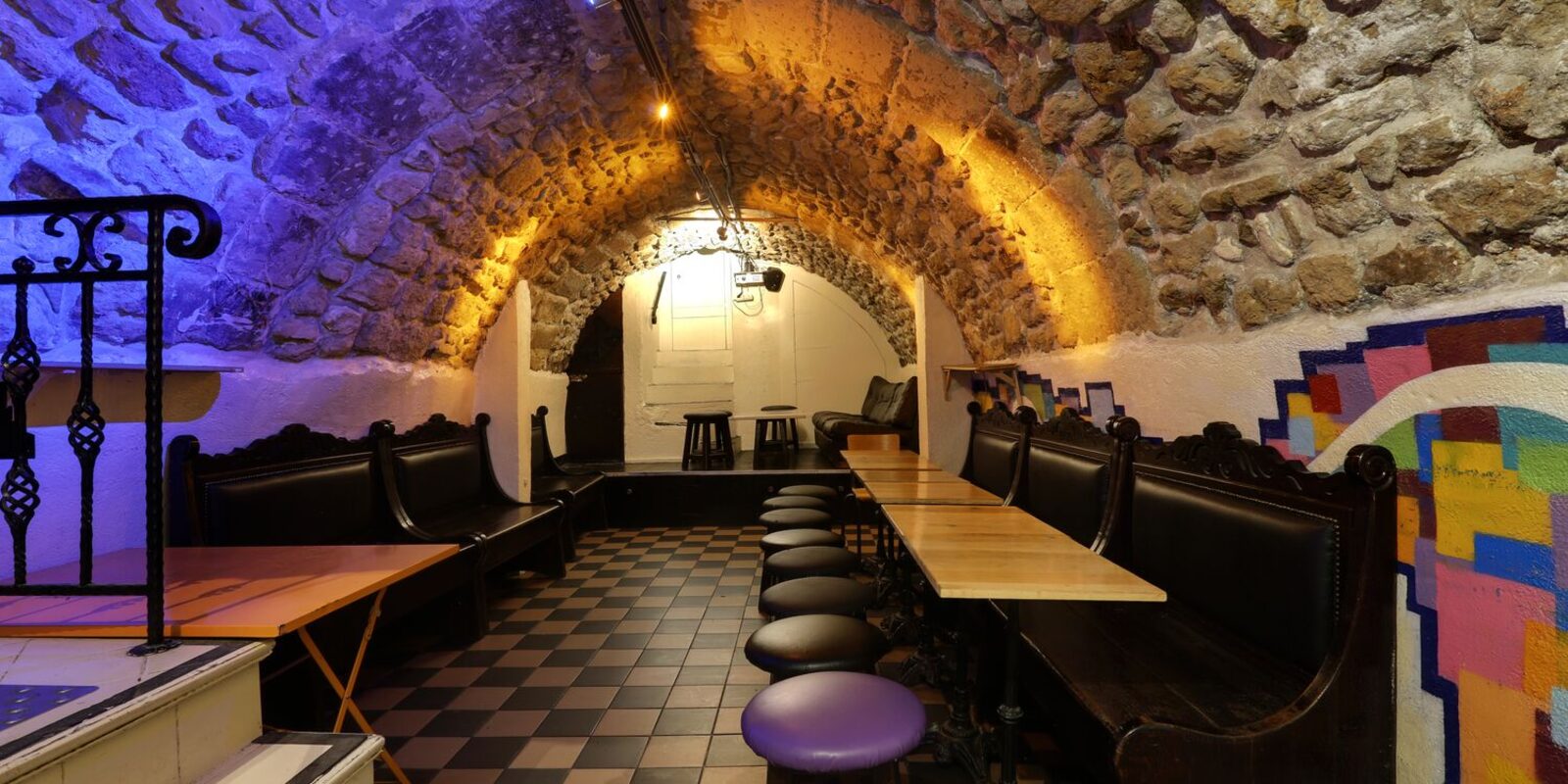 La cave voûtée en pierre, éclairée en bleu et orange