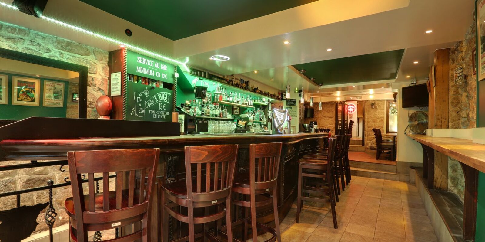 Le bar du Knight's Pub : comptoir en bois, murs verts et ardoises à la craie